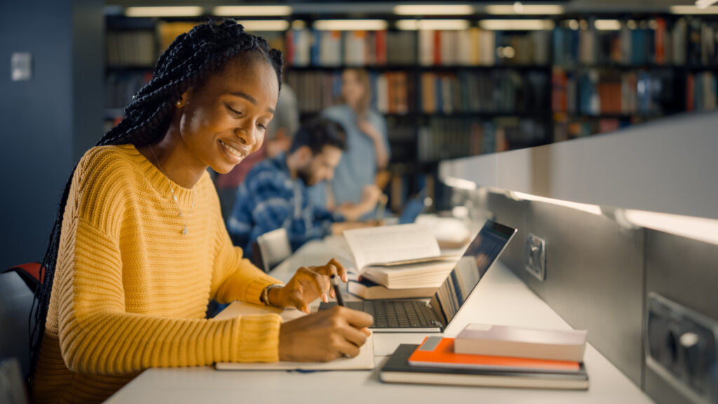 University Library: Gifted Black Girl uses Laptop, Writes Notes